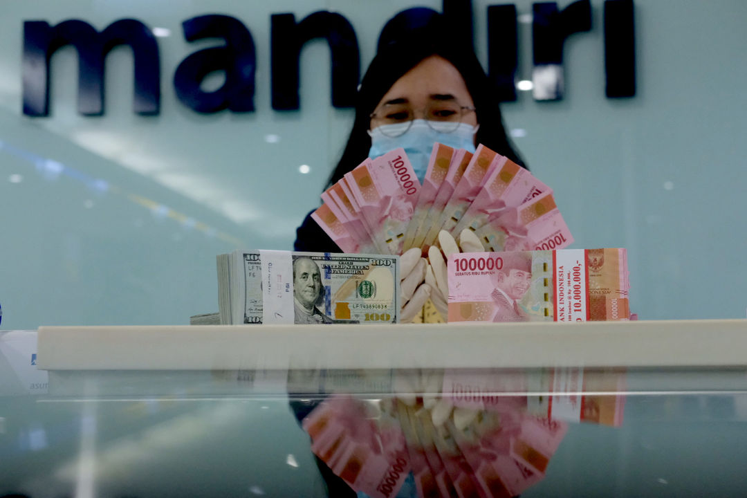 <p>Karyawati salah satu bank menunjukkan mata uang Rupiah dan Dolar di Jakarta, Selasa, 8 Juni 2021. Foto: Ismail Pohan/TrenAsia</p>
