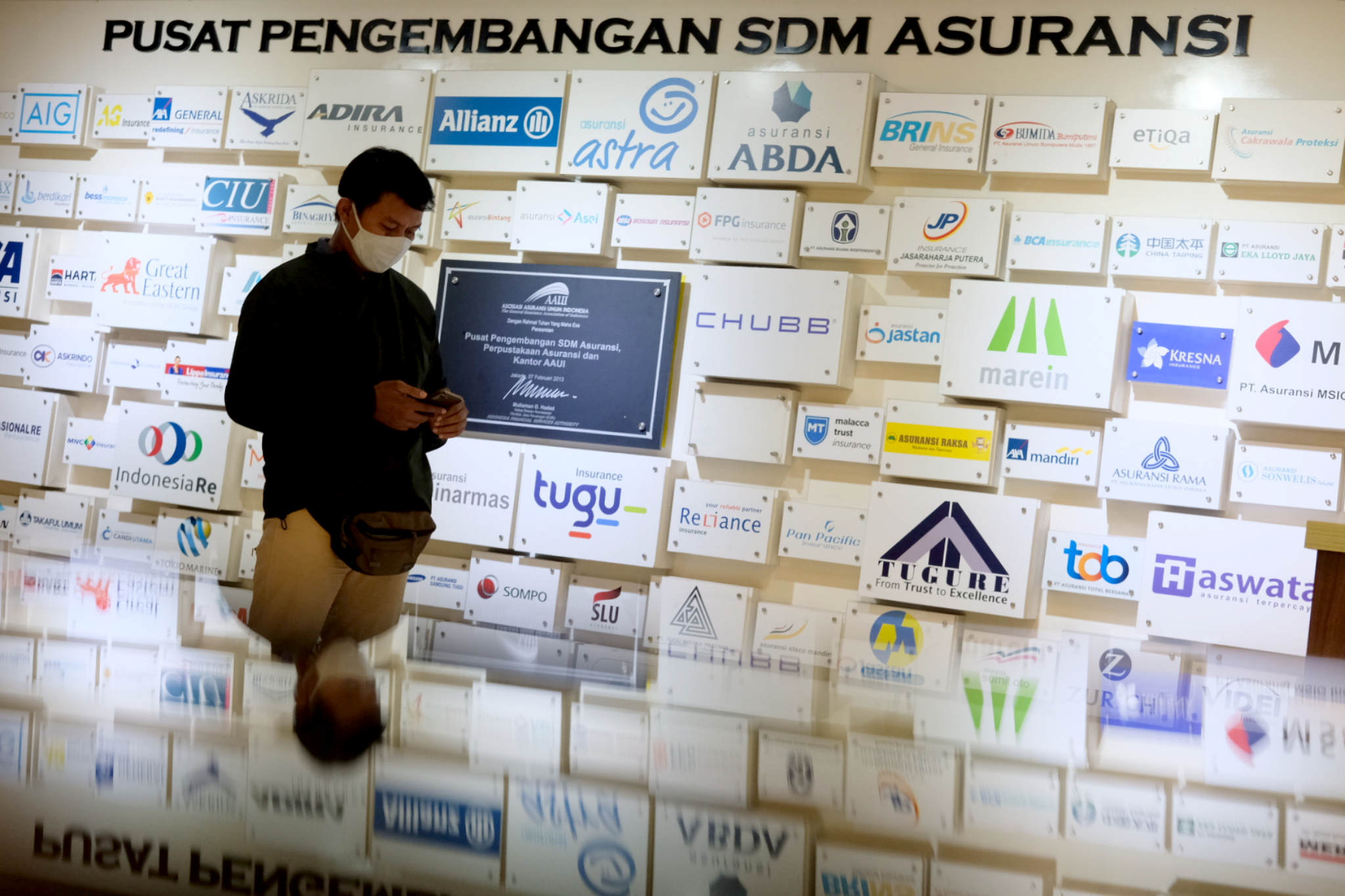 <p>Karyawan beraktivitas di dekat logo sejumlah asuransi umum di Jakarta, Senin, 28 Juni 2021. Foto: Ismail Pohan/TrenAsia</p>

