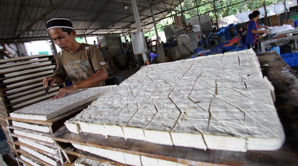 <p>Sejumlah pegawai tengah menyelesaikan proses pembuatan tahu di kawasan Pasir Putih ,Depok , Jawa Barat , Senin 7 Juni 2021. Harga kedelai impor yang masih tinggi membuat jumlah produksi tahu belum kembali normal. Foto : Panji Asmoro/TrenAsia</p>
