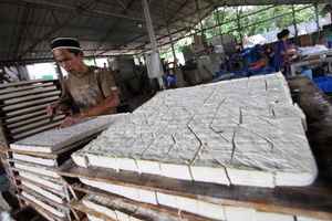 <p>Sejumlah pegawai tengah menyelesaikan proses pembuatan tahu di kawasan Pasir Putih ,Depok , Jawa Barat , Senin 7 Juni 2021. Harga kedelai impor yang masih tinggi membuat jumlah produksi tahu belum kembali normal. Foto : Panji Asmoro/TrenAsia</p>
