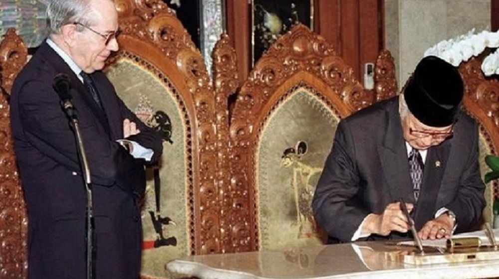 <p>Presiden Soeharto menandatangani perjanjian dengan IMF. Managing Director IMF Michel Camdessus terlihat memandanginya dengan bersedekap. / AP</p>

