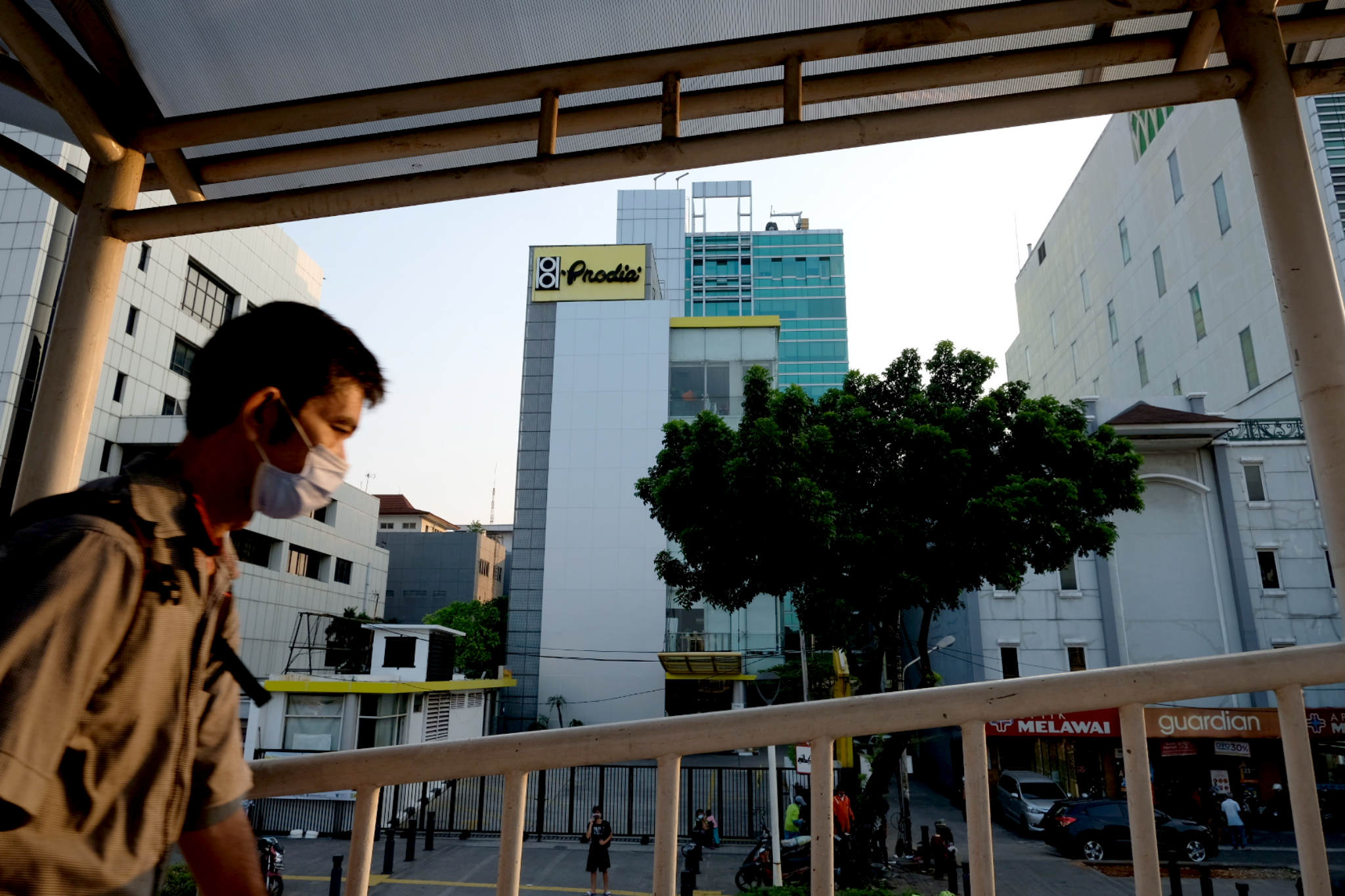 Warga melintas dengan latar gedung Health Care Prodia Tower di Jalan Kramat Raya, Senen, Jakarta, Jum'at, 16 Juli 2021. Foto: Ismail Pohan/TrenAsia