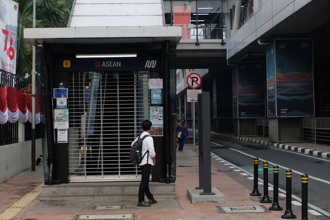 Warga memperhatikan selebaran pengumuman di stasiun MRT ASEAN yang tutup di Jalan Sisingamangaraja, Jakarta. Senin, 19 Juli 2021. Foto: Ismail Pohan/TrenAsia