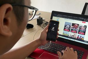 Seorang karyawan fokus mengakses aplikasi Tik Tok dan mencoba mendownload aplikasi video Tik Tok tanpa watermark di sebuah kantor, Rabu (21/7/2021).