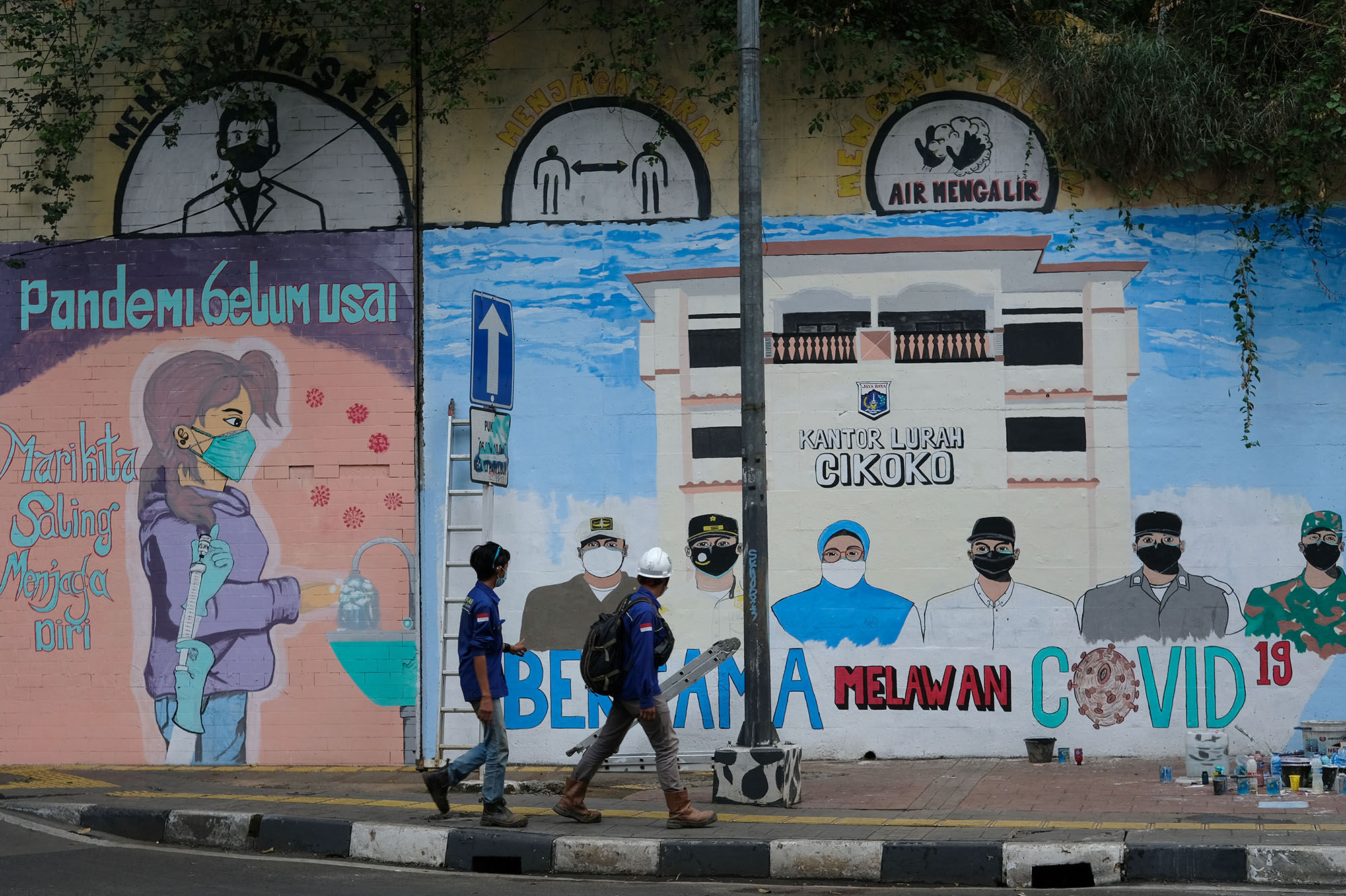 Pekerja melintas di dekat Mural bertema Lawan Covid-19 di terowongan Stasiun Cawang,  Cikoko, Jakarta Selatan, Jum'at, 23 Juli 2021. Foto: Ismail Pohan/TrenAsia