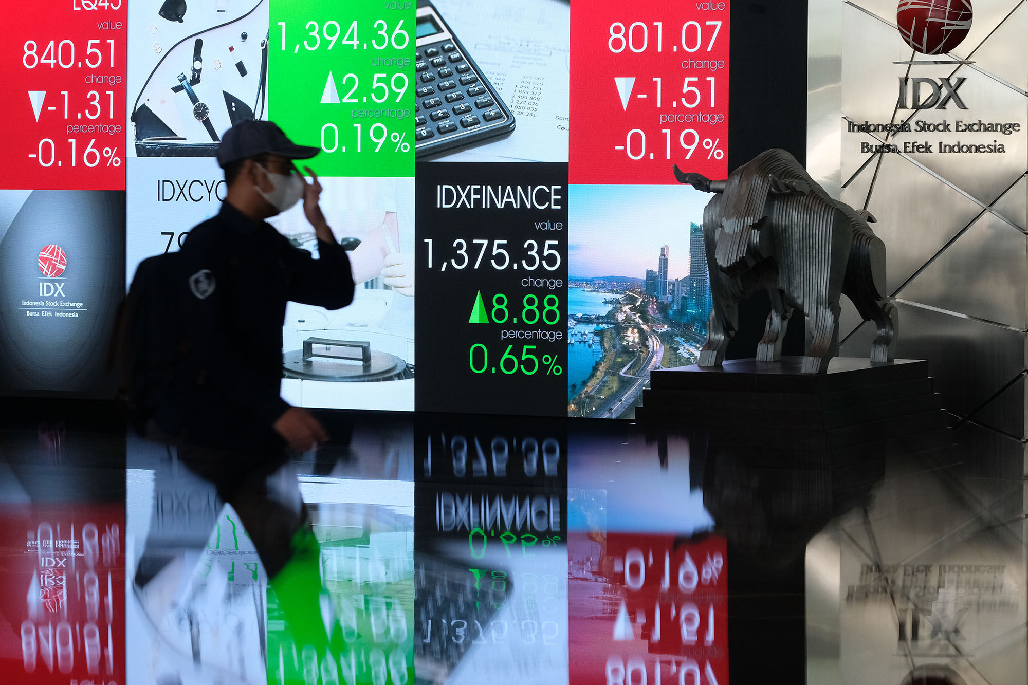 Karyawan melintas dengan latar  layar pergerakan indeks harga saham gabungan (IHSG) di gedung Bursa Efek Indonesia (BEI) Jakarta, Selasa, 27 Juli 2021. Foto: Ismail Pohan/TrenAsia