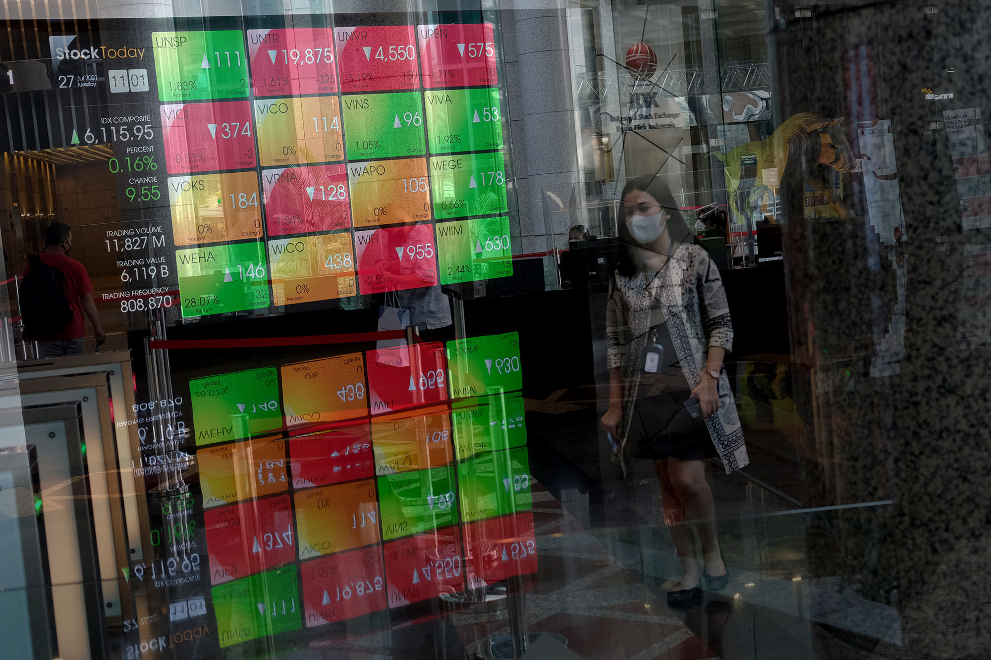 Karyawan melintas dengan latar layar pergerakan indeks harga saham gabungan (IHSG) di gedung Bursa Efek Indonesia (BEI) Jakarta, Selasa, 27 Juli 2021. Foto: Ismail Pohan/TrenAsia