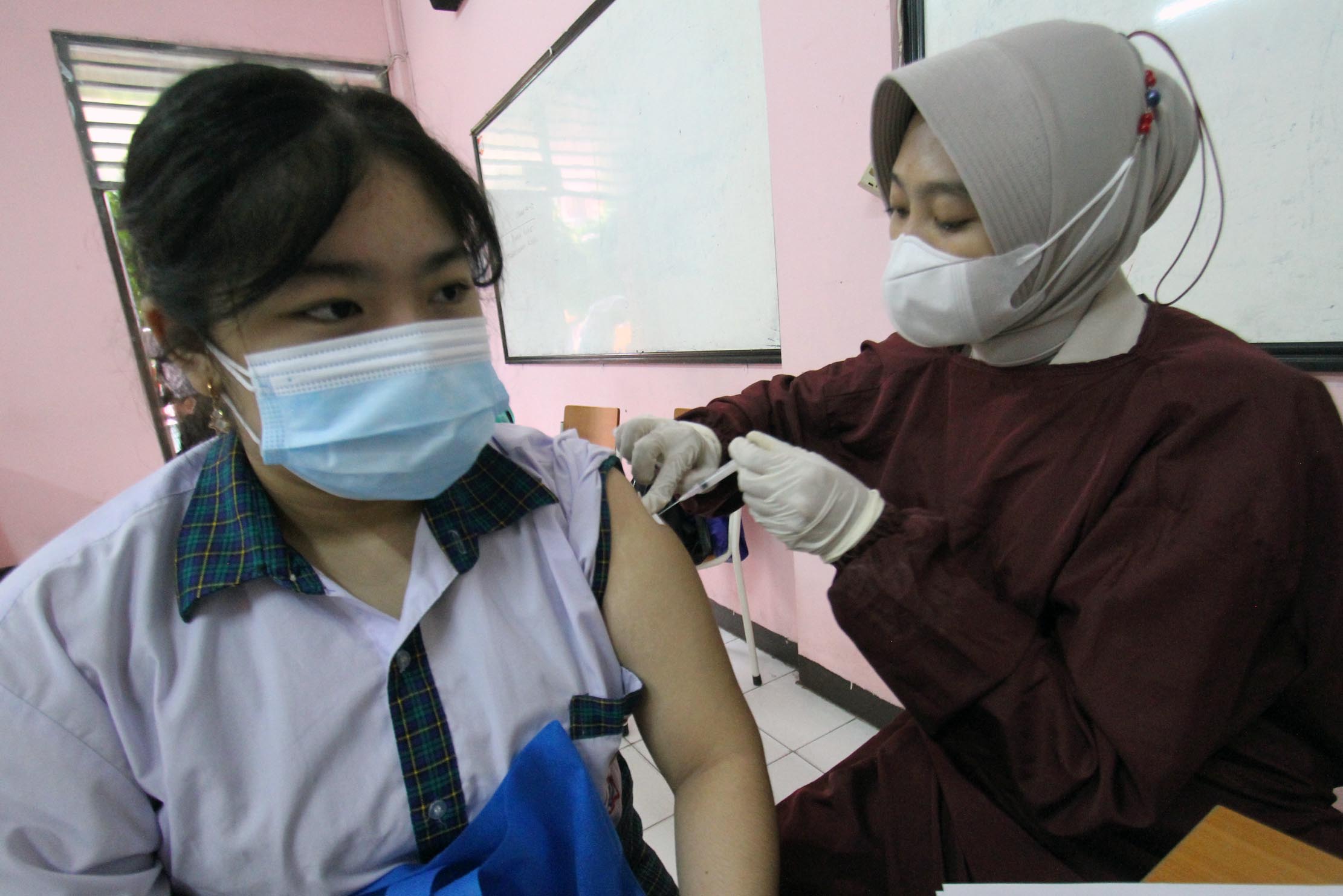 Sejumlah pelajar tengah menjalani pemeriksaan kesehatan dan penyuntikan dalam acara vaksinasi massal serentak untuk pelajar SMP dan SMA di 14 provinsi.