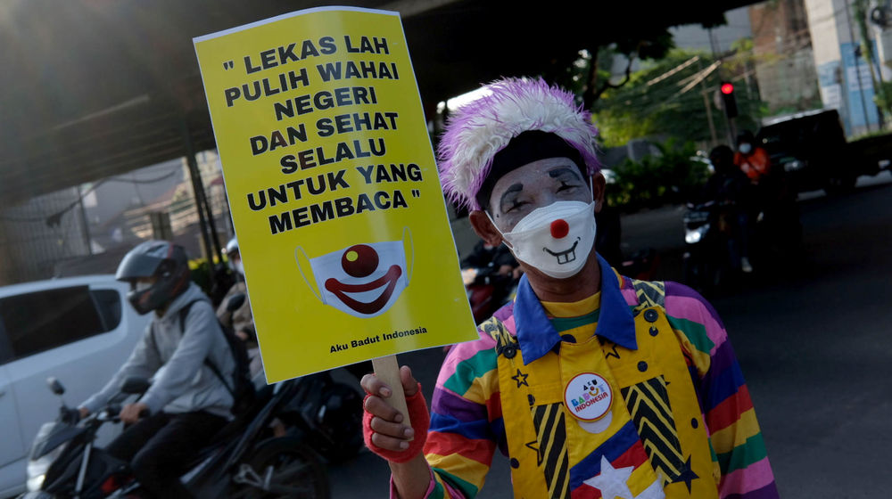 <p>Anggota Komunitas Aku Badut Indonesia(ABI) melakukan aksi kampanye untuk selalu menggunakan masker di kawasan Simpang Fatamawati, Jakarta Selatan, Senin, 12 Juli 2021. Foto: Ismail Pohan/TrenAsia</p>
