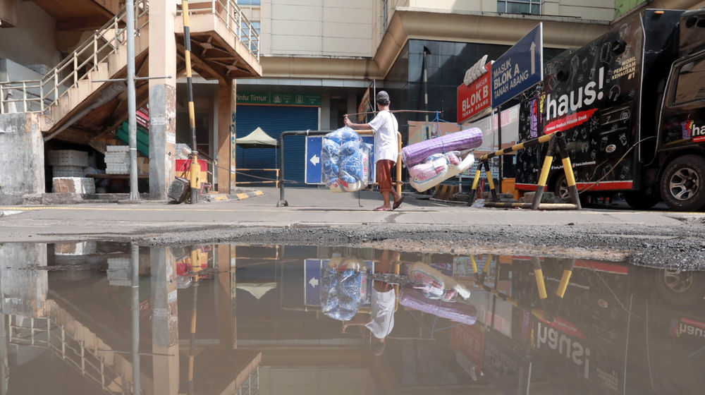 <p>Pedagang melintas di dekat pertokoan Pasar Tanah Abang yang tutup saat Pemberlakuan Pembatasan Kegiatan Masyarakat (PPKM) Darurat di Jakarta, Senin, 5 Juli 2021. Foto: Ismail Pohan/TrenAsia</p>
