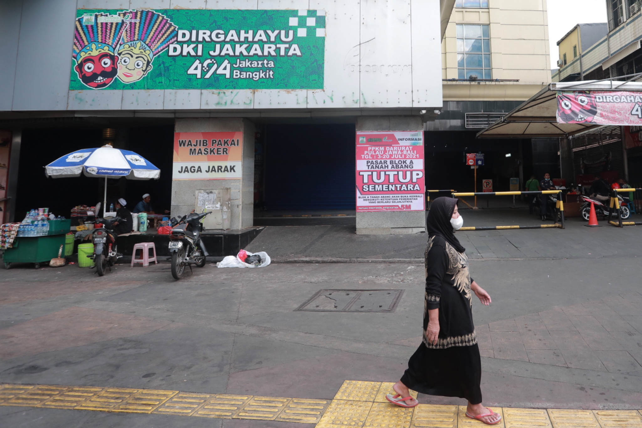 <p>Warga melintas di dekat pertokoan Pasar Tanah Abang yang tutup saat Pemberlakuan Pembatasan Kegiatan Masyarakat (PPKM) Darurat di Jakarta, Senin, 5 Juli 2021. Foto: Ismail Pohan/TrenAsia</p>
