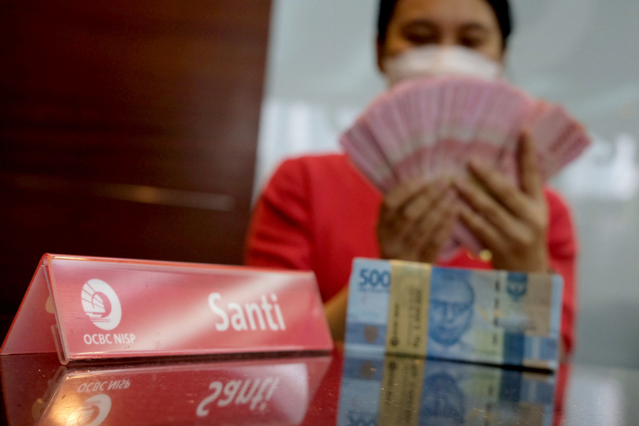 Karyawati menunjukkan mata uang Rupiah di kantor cabang Bank OCBC NISP Jakarta, Senin, 2 Agustus 2021. Foto: Ismail Pohan/TrenAsia