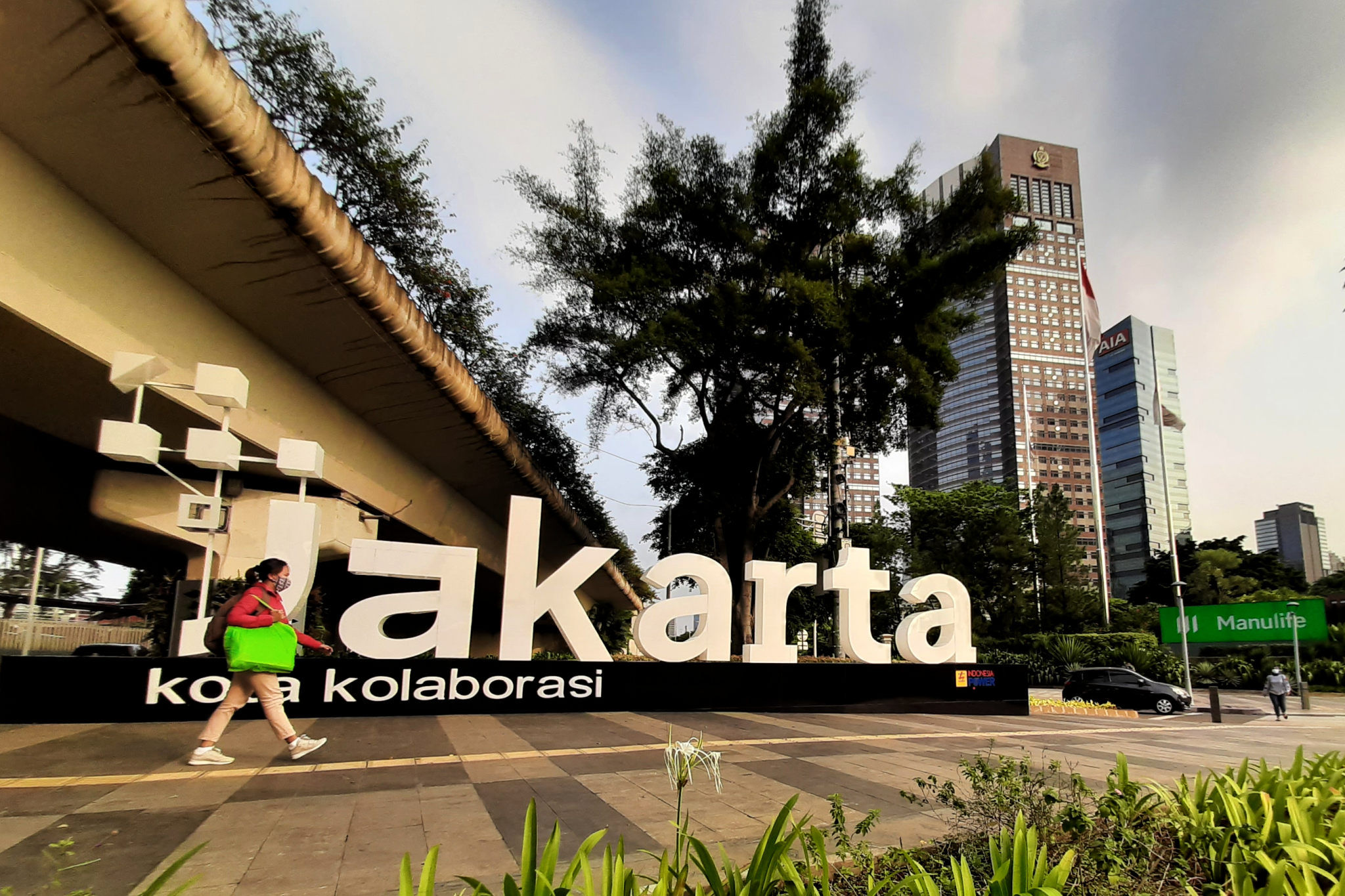 Warga melintas di dekat tulisan Jakarta Kota Kolaborasi di kawasan Jalan Sudirman, Jakarta, Senin, 2 Agustus 2021. Foto: Ismail Pohan/TrenAsia