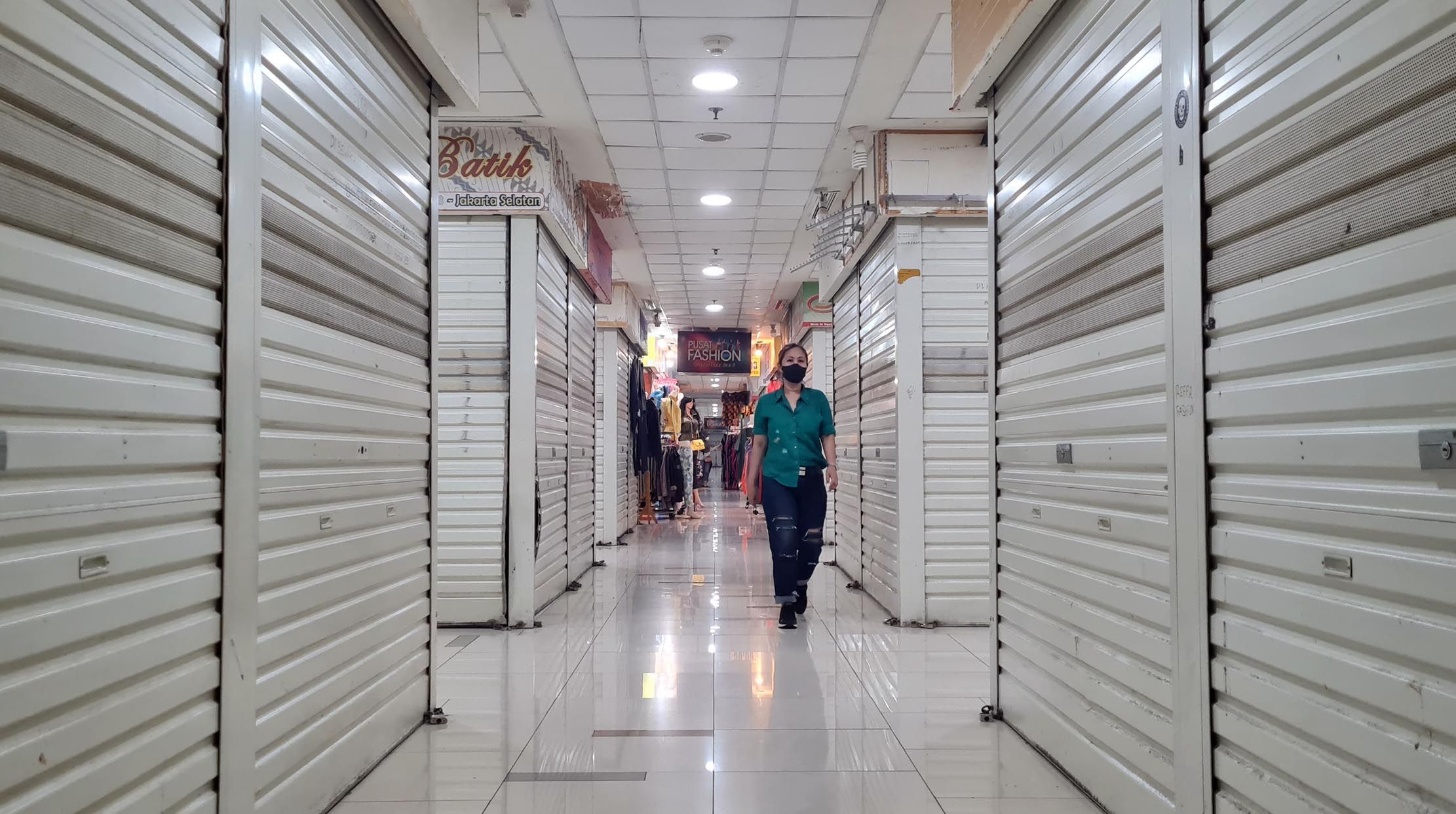 Nampak pengunjung melintas di deretan kios-kios di kawasan Blok M Square yang sebagian tidak beroperasi imbas dari lesunya pembeli dan PPKM yang masih terus diperpanjang, Senin 9 Agustus 2021. Foto : Panji Asmoro/TrenAsia