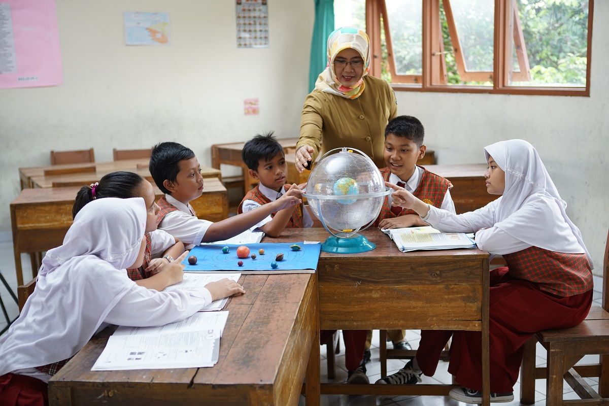 Seorang guru tengah memberikan pembelajaran kepada anak-anak didinya.