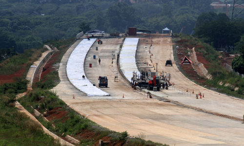 Sejumlah pekerja dengan alat berat tengah menyelesaikan proyek pembangunan Tol Serpong Balaraja di kawasan Cilenggang TangSel, Kamis 26 Agustus 2021. Foto : Panji Asmoro/TrenAsia