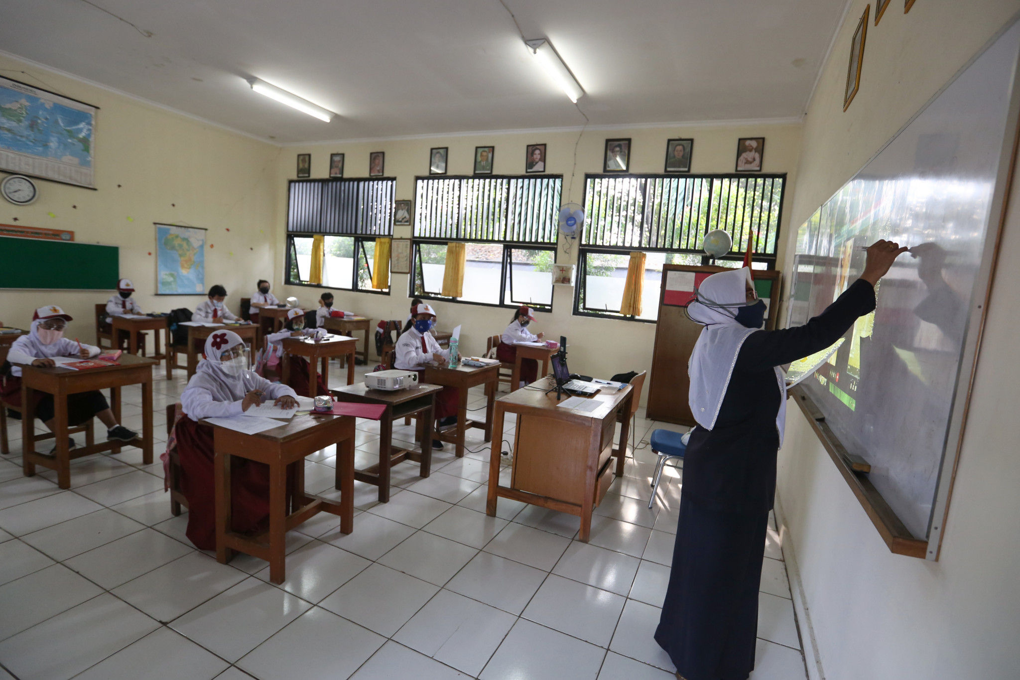 Guru memberikan materi pelajaran kepada Siswa Sekolah Dasar yang mengikuti Sekolah Tatap Muka Perdana di SDN 14 Pagi, Pondok Labu, Jakarta Selatan, Senin, 30 Agustus 2021. Foto: Ismail Pohan/TrenAsia