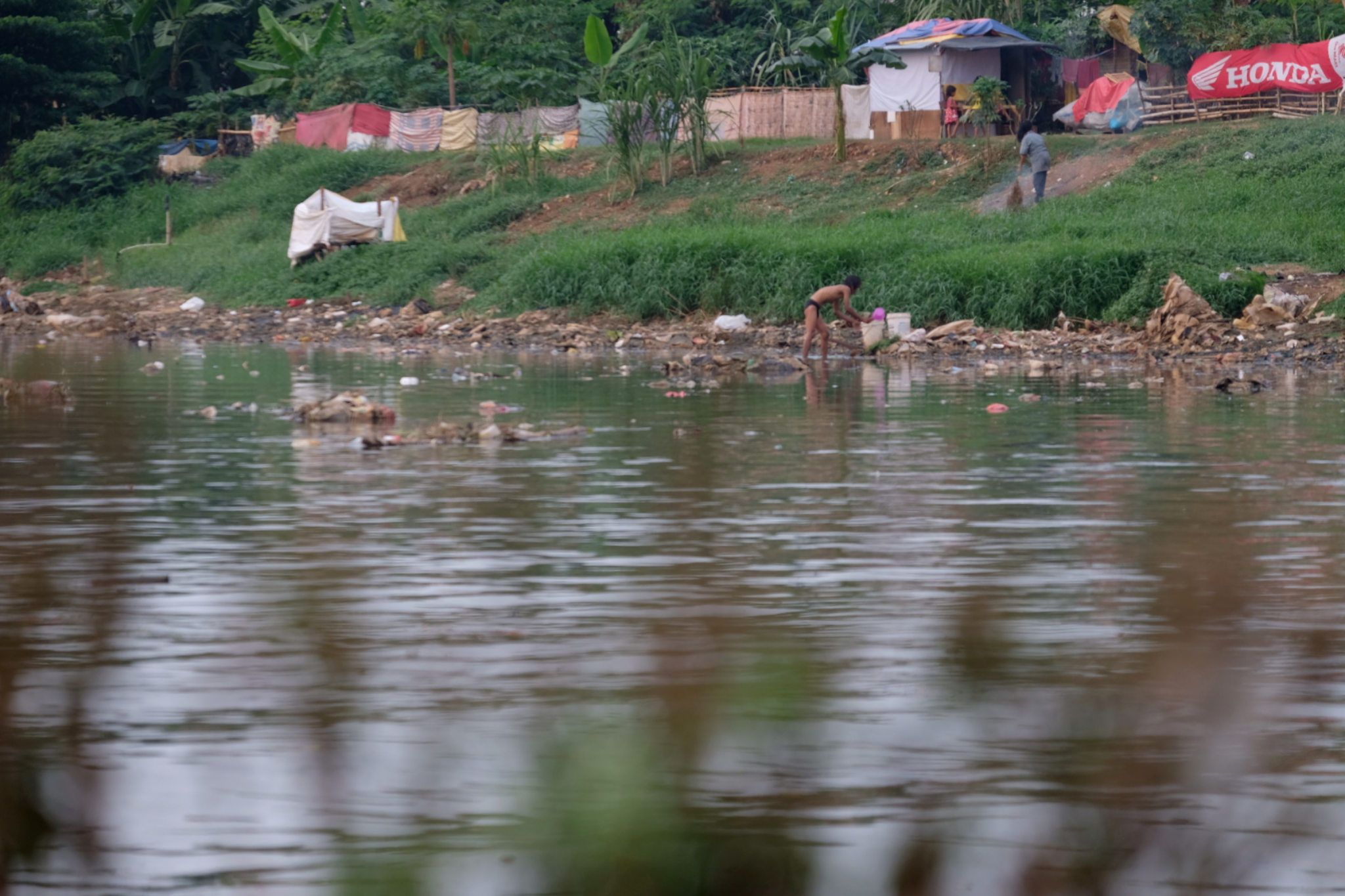 Warga memanfaatkan air sungai untuk aktivitas MCK dari bantaran Kanal Banjir Barat, Jakarta, Selasa, 31 Agustus 2021. Foto: Ismail Pohan/TrenAsia