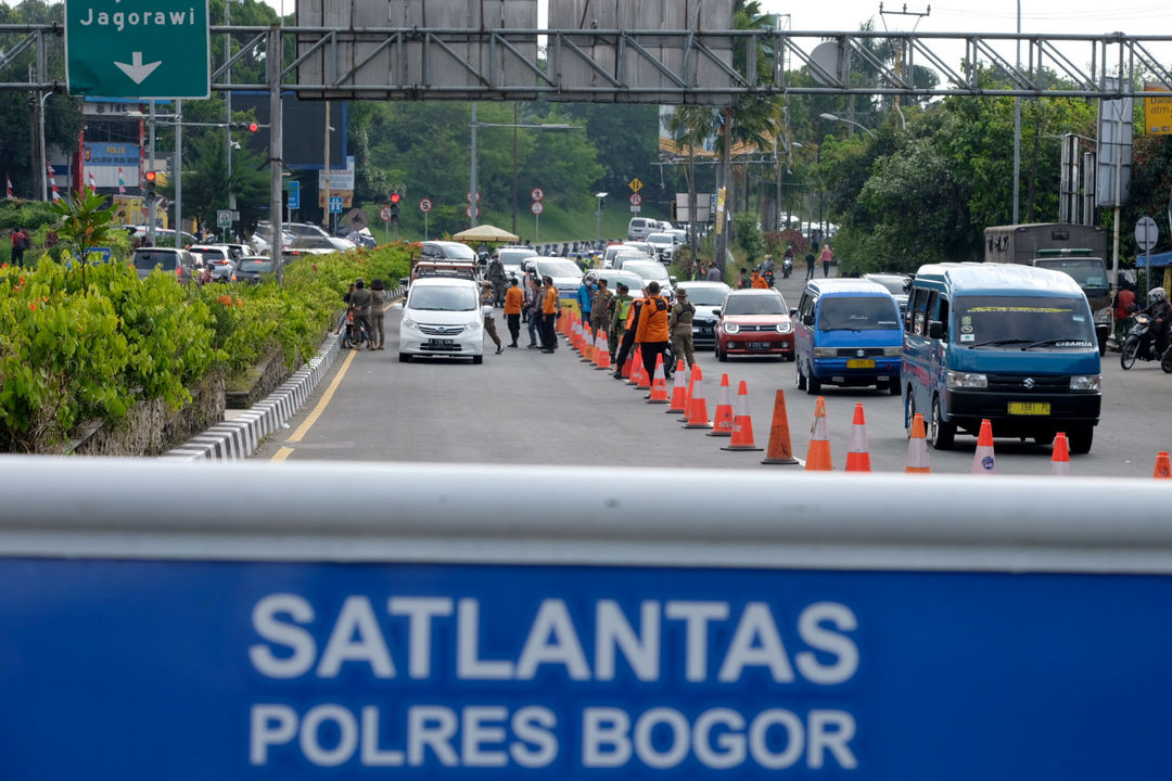 Petugas gabungan mengarahkan kendaraan saat uji coba penerapan sistem ganjil genap di Jalan Raya Puncak, Gadog, Ciawi, Kabupaten Bogor, Jawa Barat, Jumat, 3 September 2021. Foto: Ismail Pohan/TrenAsia