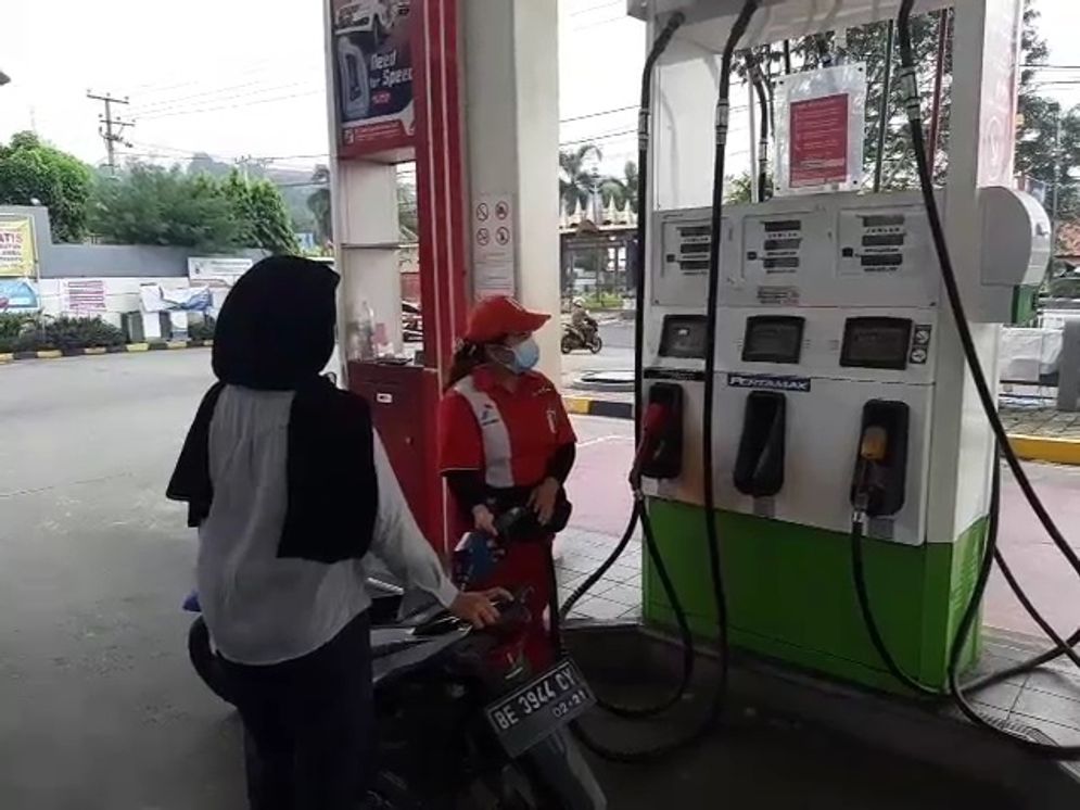 Petugas SPBU sedang melayani konsumen pembeli bahan bakar minyak