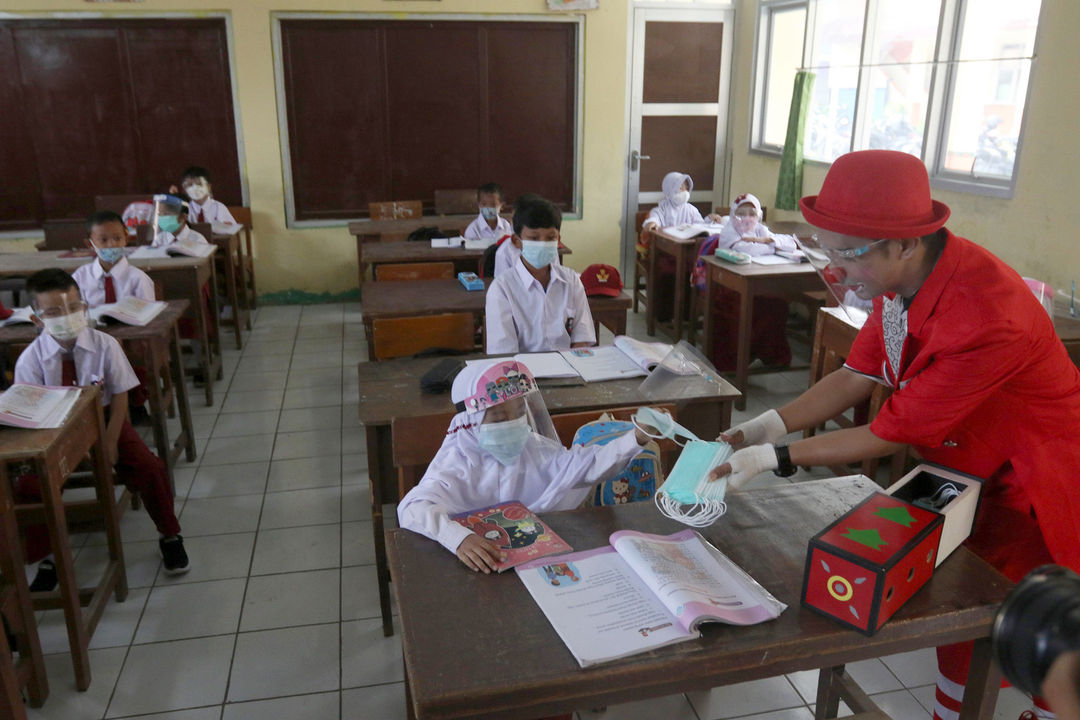 Anggota Aku Badut Indonesia (ABI) mmbagikan masker saat melakukan kampanye protokol kesehatan 3M untuk siswa yang mengikuti pembelajaran tatap muka (PTM) di SDN 03 Citayam, Kabupaten Bogor, Jawa Barat, Senin, 6 September 2021. Foto: Ismail Pohan/TrenAsia