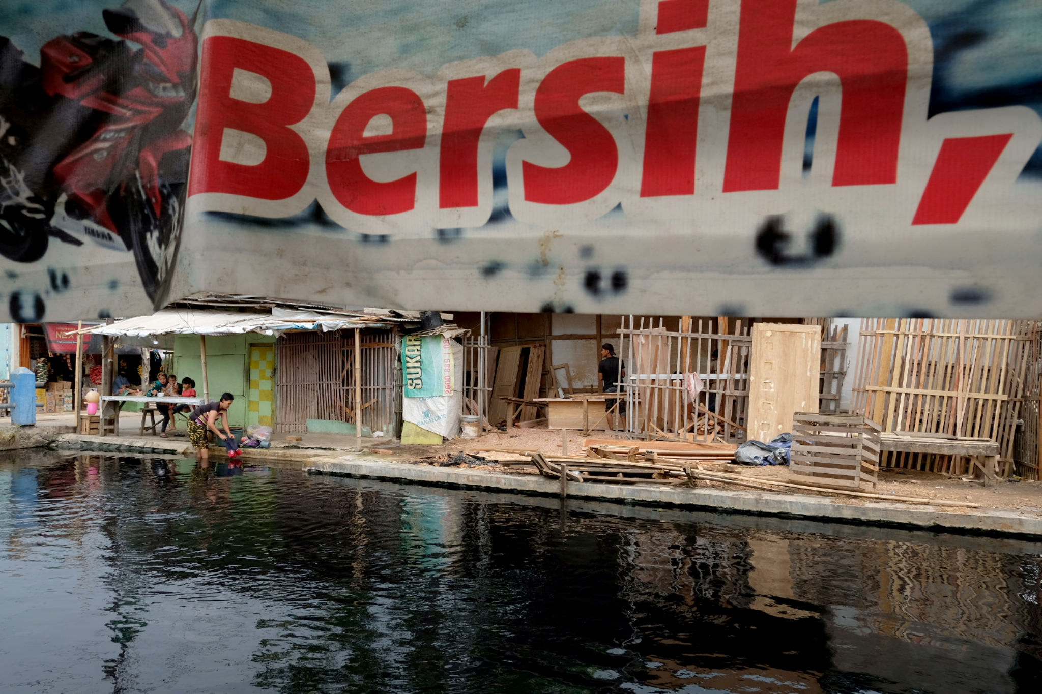 Warga memanfaatkan air kali yang berwana hitam dan berbau tak sedap untuk mencuci di Desa Sukaraya, Karangbahagia, Kabupaten Bekasi, Jawa Barat, Selasa, 7 November 2021. Foto: Ismail Pohan/TrenAsia