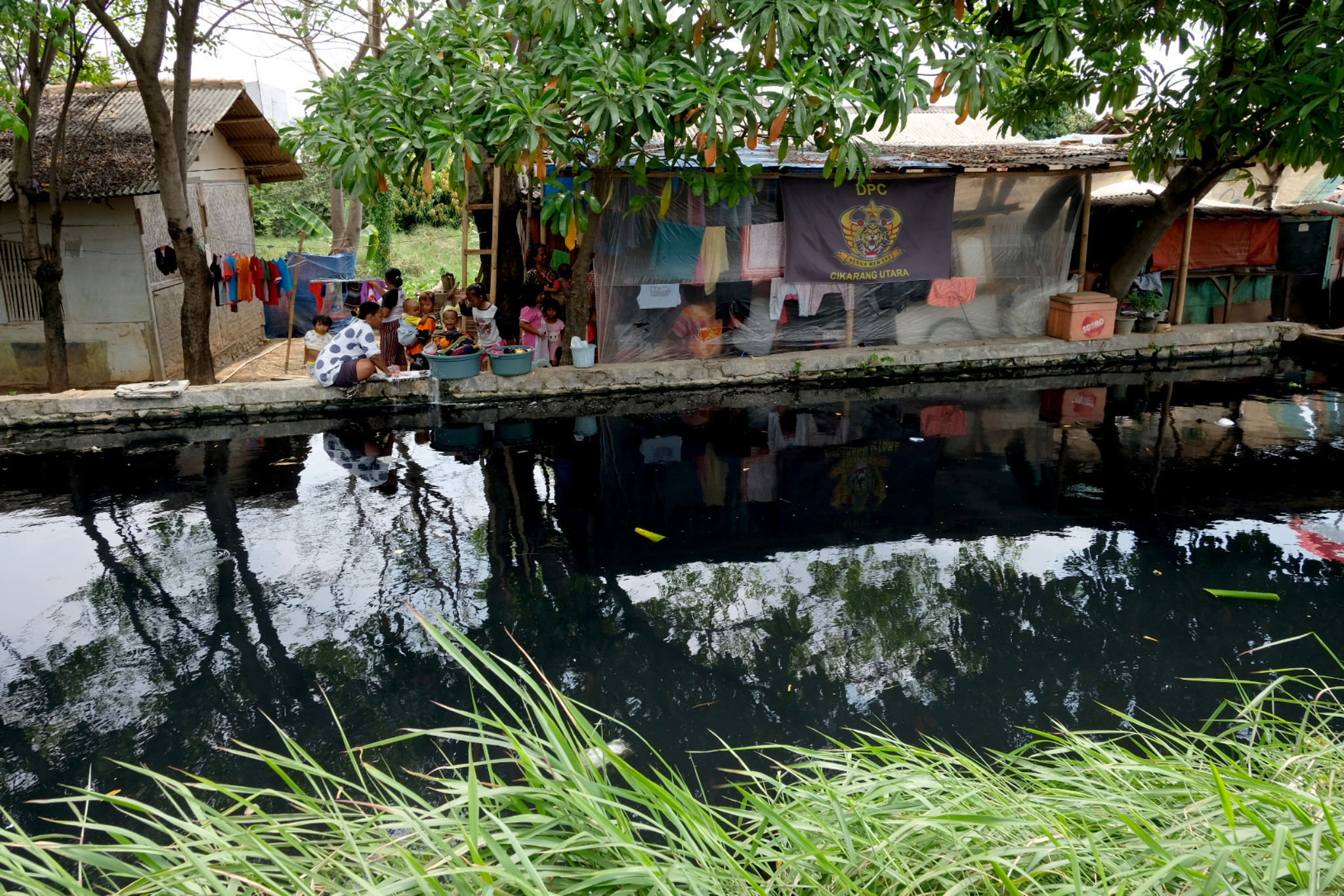 Warga memanfaatkan air kali yang berwana hitam dan berbau tak sedap untuk mencuci di Desa Sukaraya, Karangbahagia, Kabupaten Bekasi, Jawa Barat, Selasa, 7 November 2021. Foto: Ismail Pohan/TrenAsia