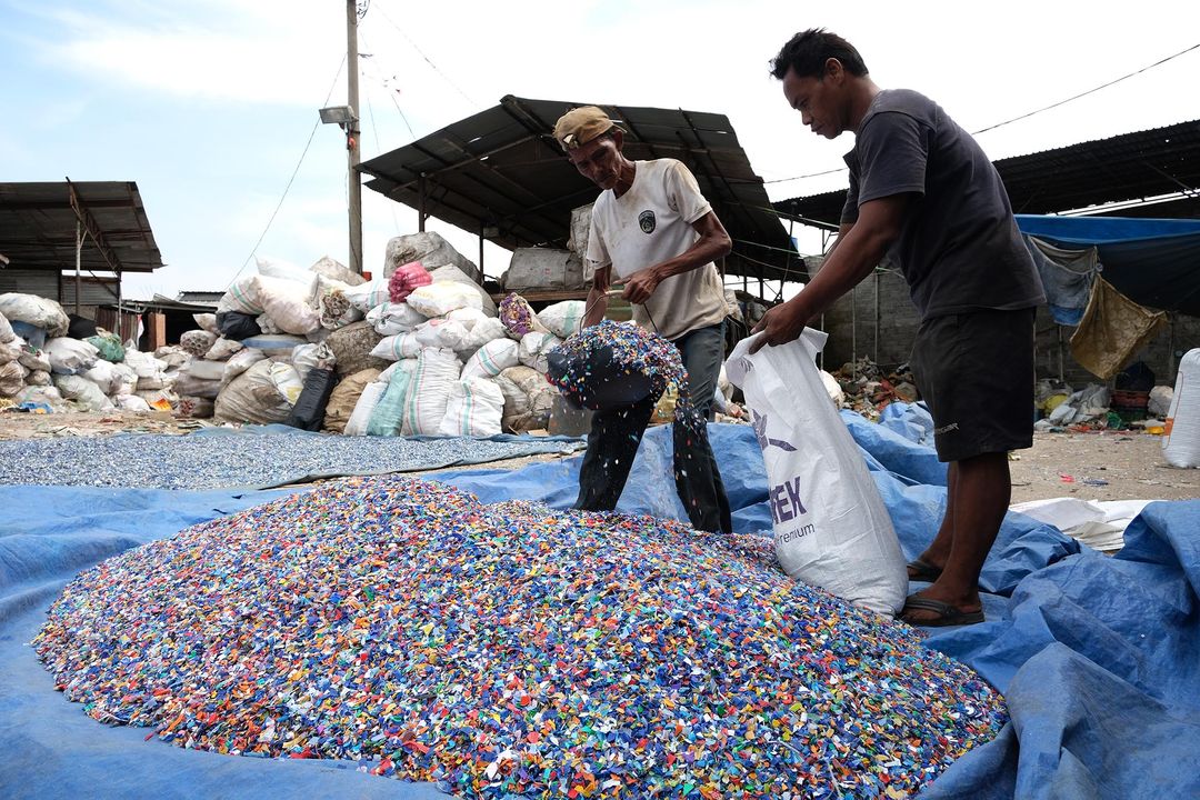 Pekerja memasukkan leburan sampah plastik yang sudah dijemur kedalam karung untuk kemudian ditimbang di gudang pengolahan sampah plastik kawasan Bekasi, Selasa, 14 September 2021. Foto: Ismail Pohan/TrenAsia