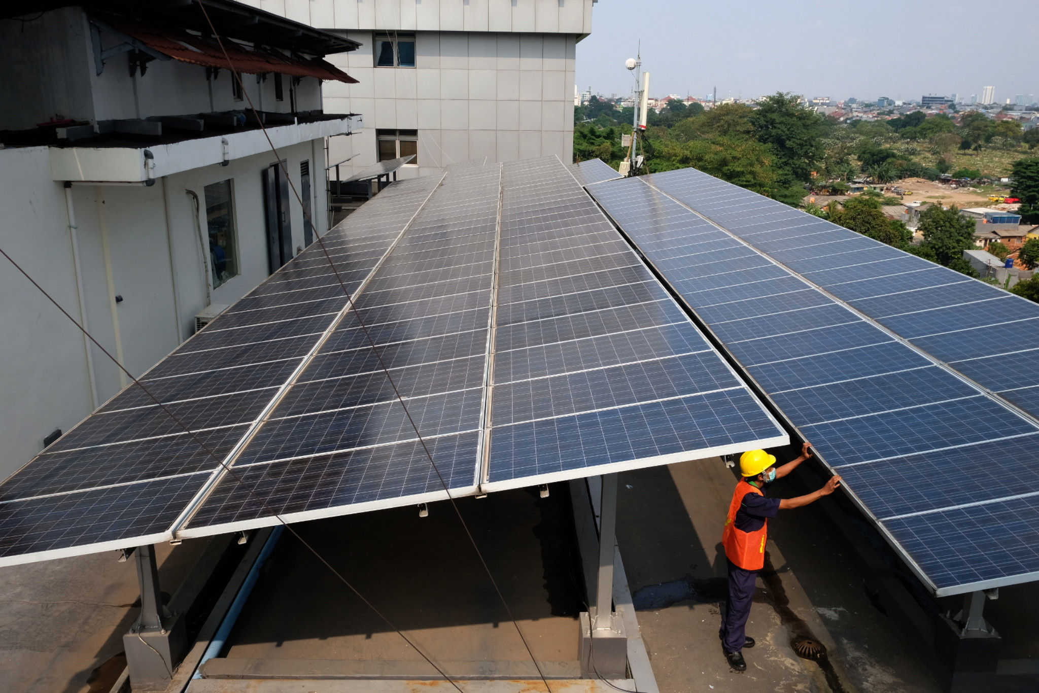 Pekerja memeriksa intalasi panel surya di gedung Dirjen Ketenagalistrikan Kementerian ESDM, di Jalan Rasuna Said, Kuningan, Jakarta, Senin, 27 September 2021. Foto: Ismail Pohan/TrenAsia