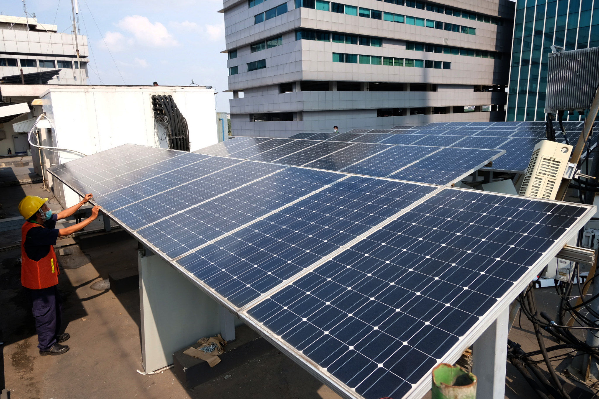 Pekerja memeriksa intalasi panel surya di gedung Dirjen Ketenagalistrikan Kementerian ESDM, di Jalan Rasuna Said, Kuningan, Jakarta, Senin, 27 September 2021. Foto: Ismail Pohan/TrenAsia