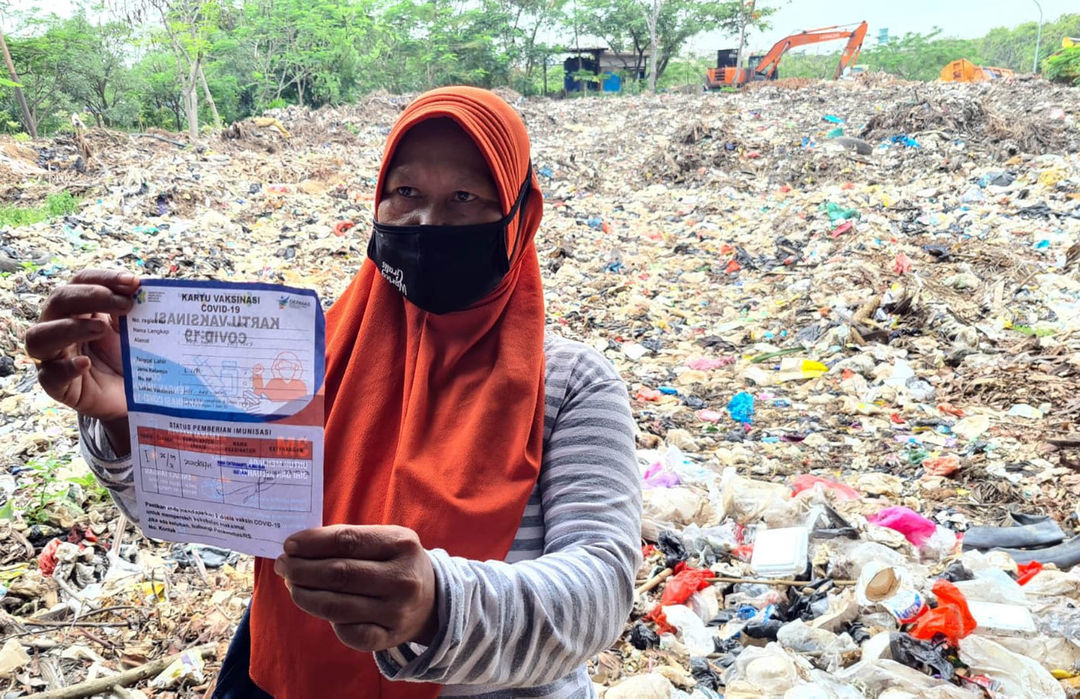 Nampak warga menunjukkan surat vaksin usai disuntik Vaksin COVID-19 pada pelaksanaan vaksinasi untuk komunitas pemulung dan pengepul sampah di Tempat Pembuangan Akhir (TPA) Sampah Rawa Kucing Tangerang yang merupakan kerjasama antara Pemkot Tangerang dan Danone Indonesia, Selasa 28 September 2021. Foto : Panji Asmoro/TrenAsia