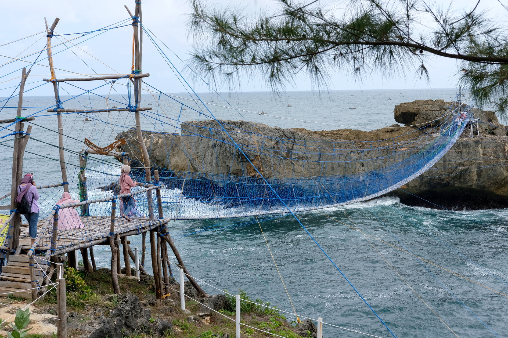 Wisatawan melintasi jembatan gantung di Pantai Watu Bale, Kecamatan Tulakan, Kabupaten Pacitan, Jawa Timur, Sabtu, 9 Oktober 2021. Foto: Ismail Pohan/TrenAsia