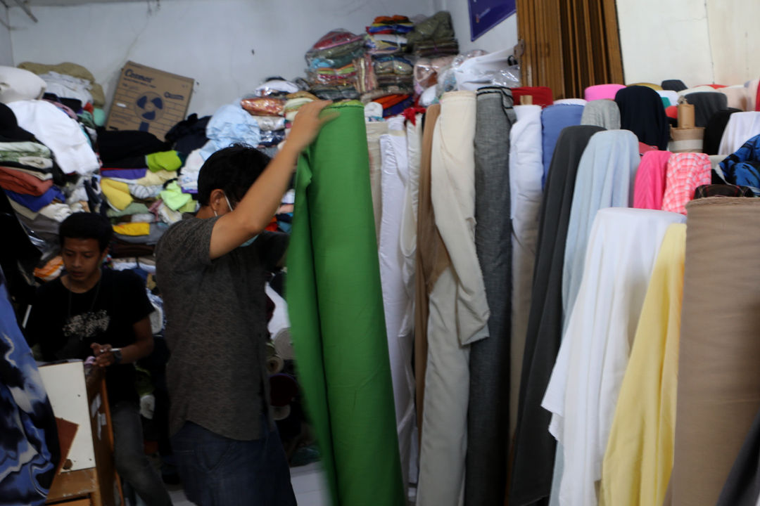 Pedangang menata bahan kain yang dijual di sentra grosir tekstil pasar Cipadu, Tangerang, Banten, Kamis, 14 Oktober 2021. Foto: Ismail Pohan/TrenAsia