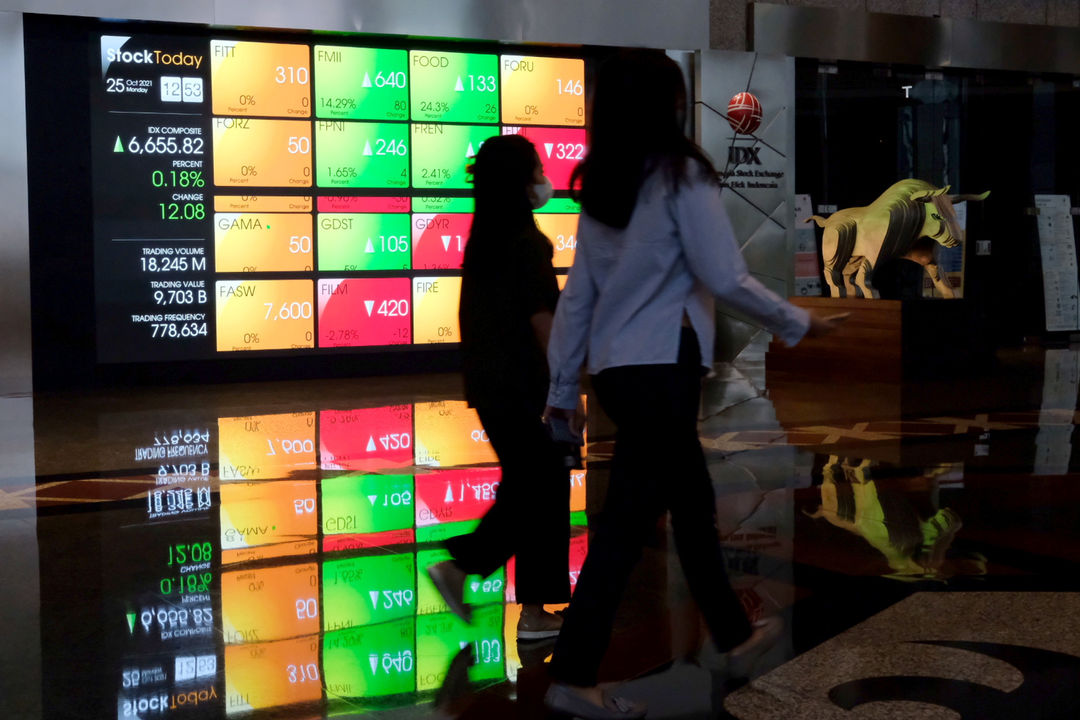 Karyawan melintas dengan latar layar pergerakan indeks harga saham gabungan (IHSG) di gedung Bursa Efek Indonesia (BEI) Jakarta, Senin, 25 Oktober 2021. Foto: Ismail Pohan/TrenAsia