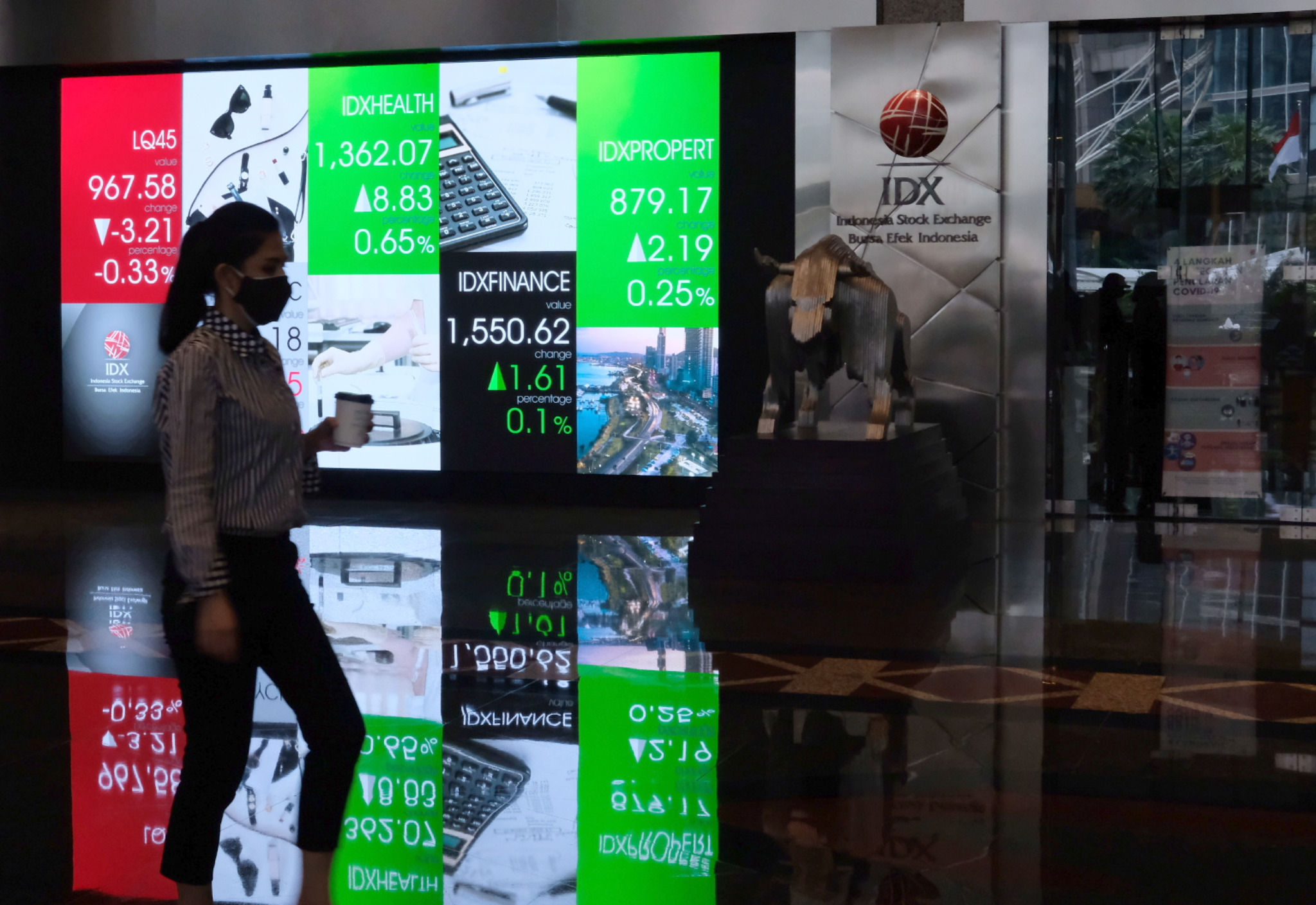 Karyawan melintas dengan latar layar pergerakan indeks harga saham gabungan (IHSG) di gedung Bursa Efek Indonesia (BEI) Jakarta, Senin, 25 Oktober 2021. Foto: Ismail Pohan/TrenAsia