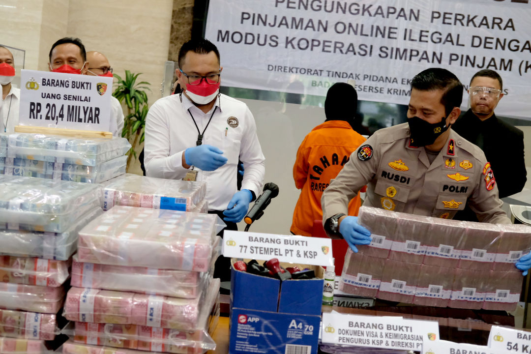 Petugas kepolisian menunjukkan barang bukti uang  dan pelaku penipuan pinjaman online ilegal, saat rilis kasus tersebut di gedung Mabes Polri, Jakarta, Senin, 25 Oktober 2021. Foto: Ismail Pohan/TrenAsia