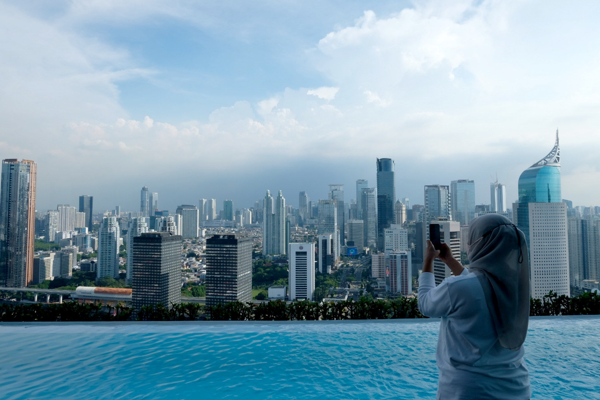 Warga mengambil gambar lanskap gedung bertingkat dan perkantoran di Jakarta, Senin, 1 November 2021. Foto: Ismail Pohan/TrenAsia