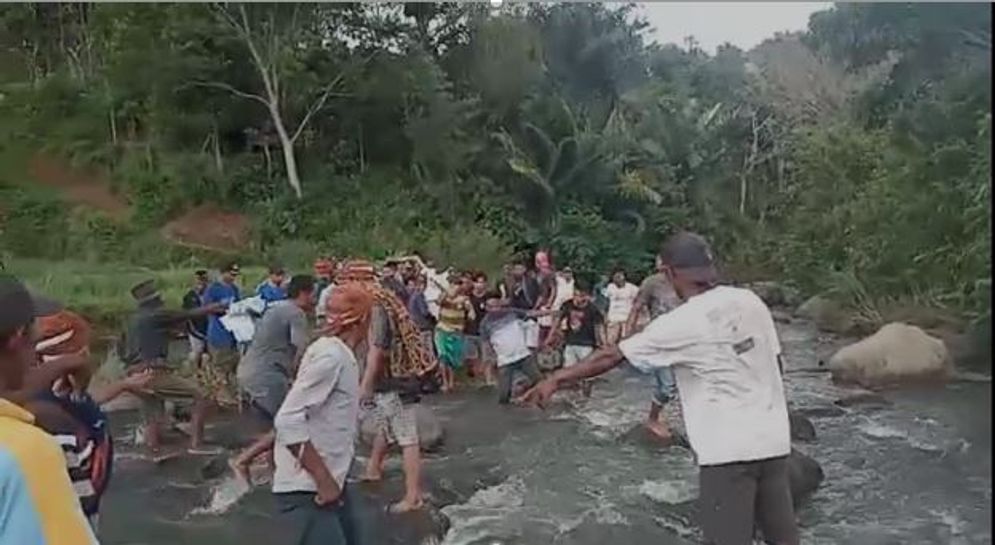 Warga Kampung Jewong, Desa Kolang, Kecamatan Kuwus Barat, Kabupaten Manggarai Barat menandu jenazah seorang laki-laki melalui sungai karena tak ada akses jalan, Seni 1 November 2021.