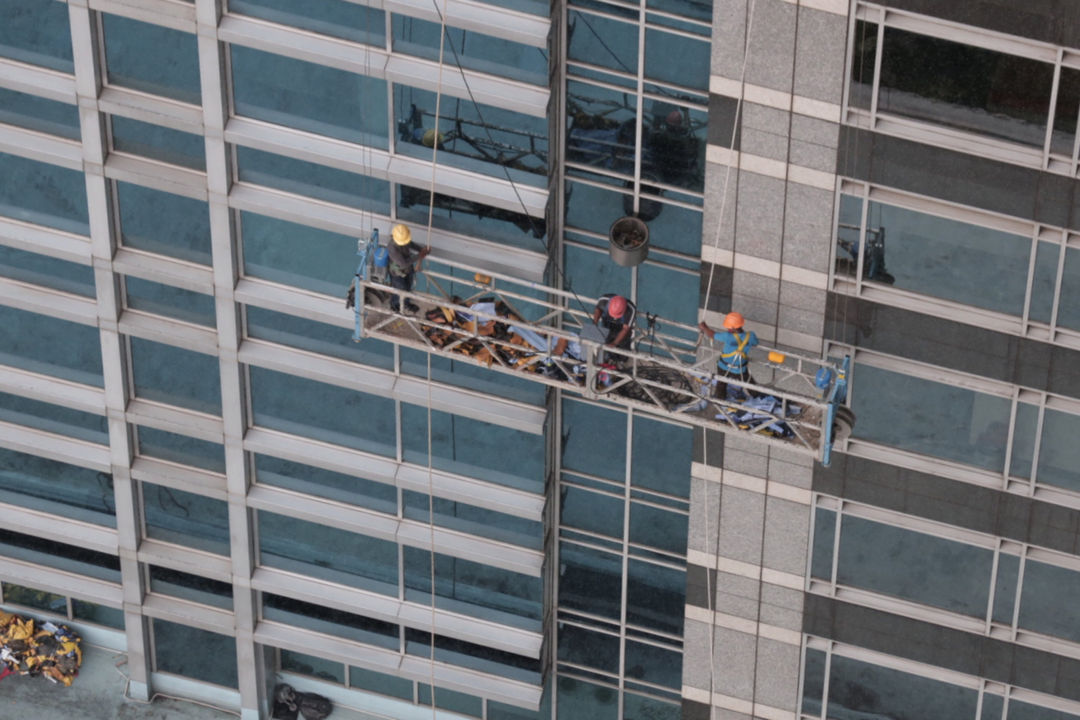 Pekerja melakukan perawatan gedung dengan menggunakan gondola di kawasan Sudirman , Jakarta, Jum'at, 5 November 2021. Foto: Ismail Pohan/TrenAsia