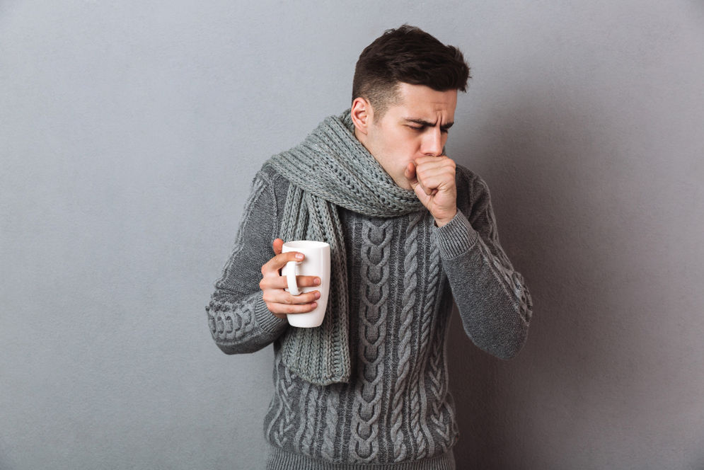 sick-man-sweater-scarf-holding-cup-tea-while-having-cough.jpg