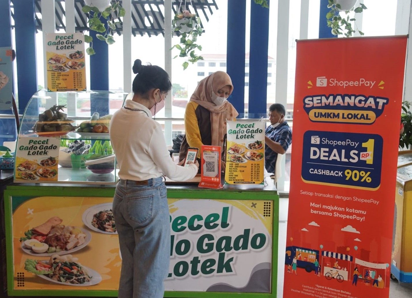 Seorang pengunjung sedang melakukan transaksi menggunakan ShopeePay sembari menikmati promo Cashback 90% di sentra kuliner Taste Food Malioboro