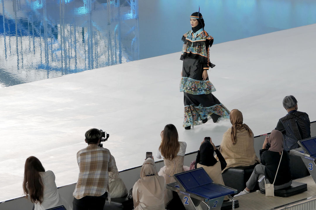 Model memperagakan busana muslim diatas catwalk saat gelaran Embracing Jakarta Muslim Fashion Week di stadion Aquatic Gelora Bung Karno (GBK), Jakarta, Kamis, 18 November 2021. Foto: Ismail Pohan/TrenAsia