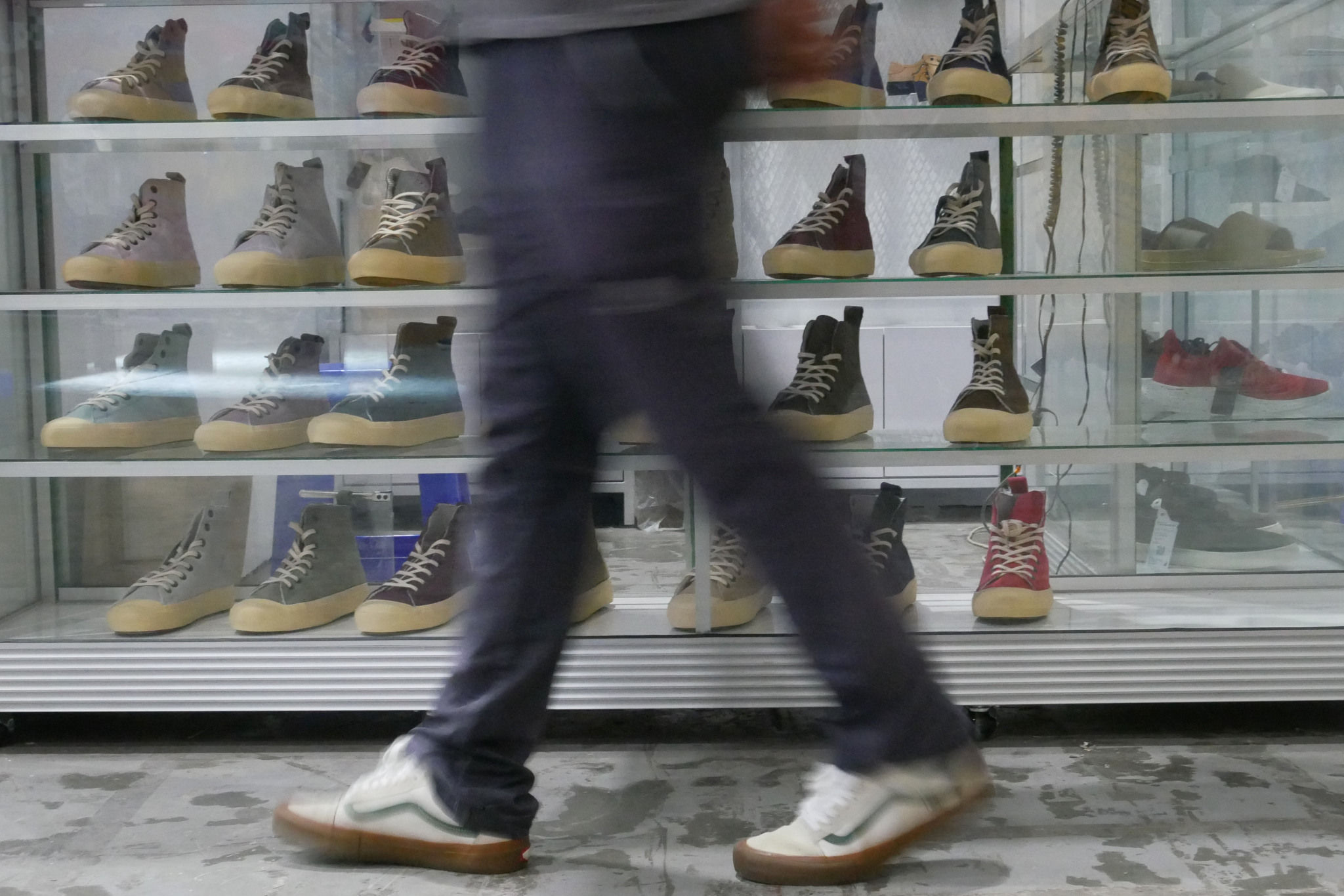 Pengunjung melintas didekat koleksi sepatu salah satu booth perserta pada gelaran Urban Sneaker Society 2021, di JCC Senayan, Jakarta, Minggu, 5 Desember 2021. Foto: Ismail Pohan/TrenAsia