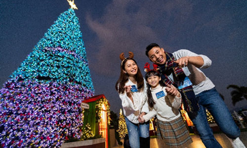 Potret keluarga di depan pohon Natal Raksasa Art Park WKCD.png