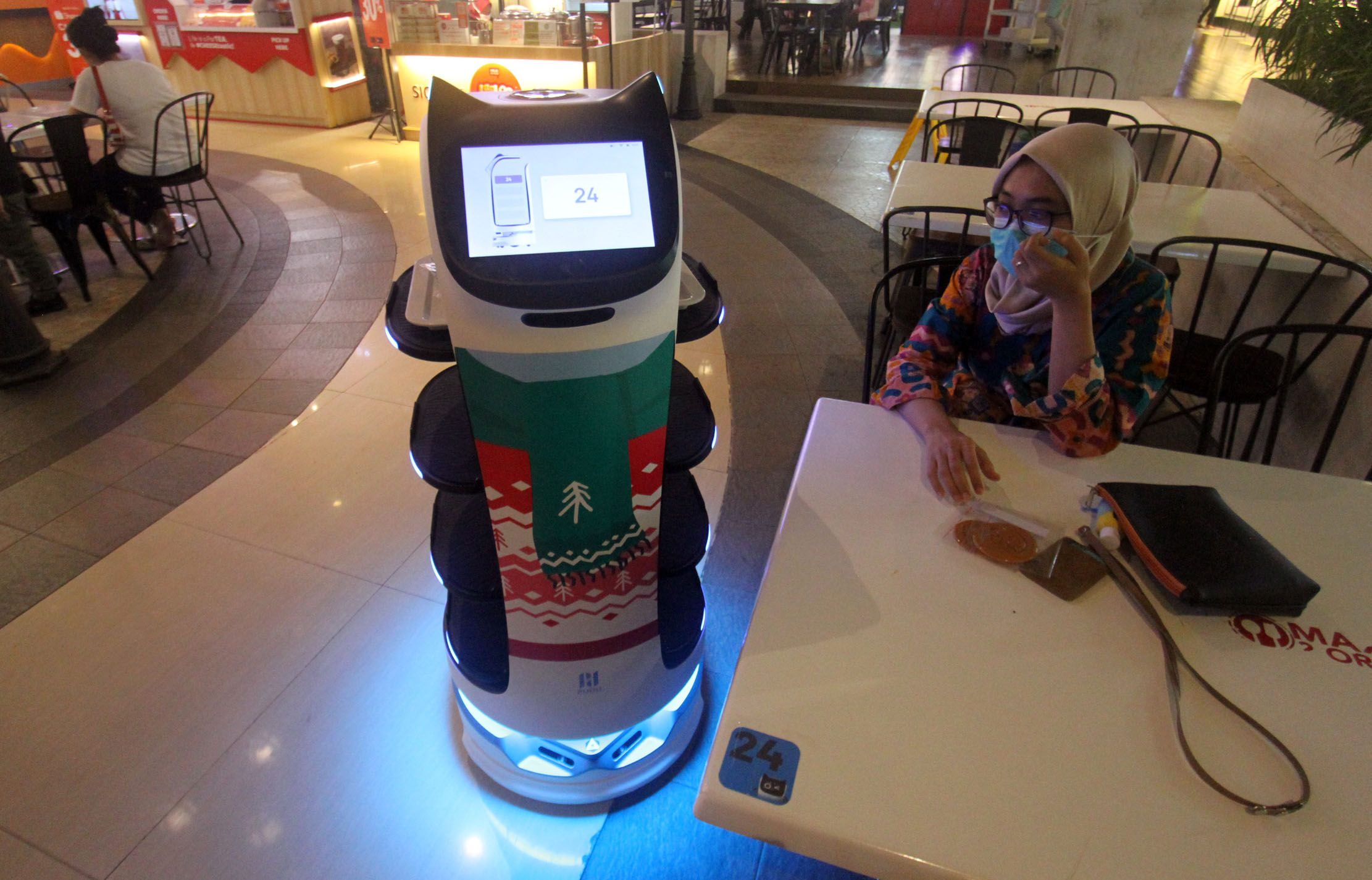 Robot pramusaji berhias nuansa natal siap melayani pengunjung yang memesan makanan. Foto : Panji Asmoro/TrenAsia