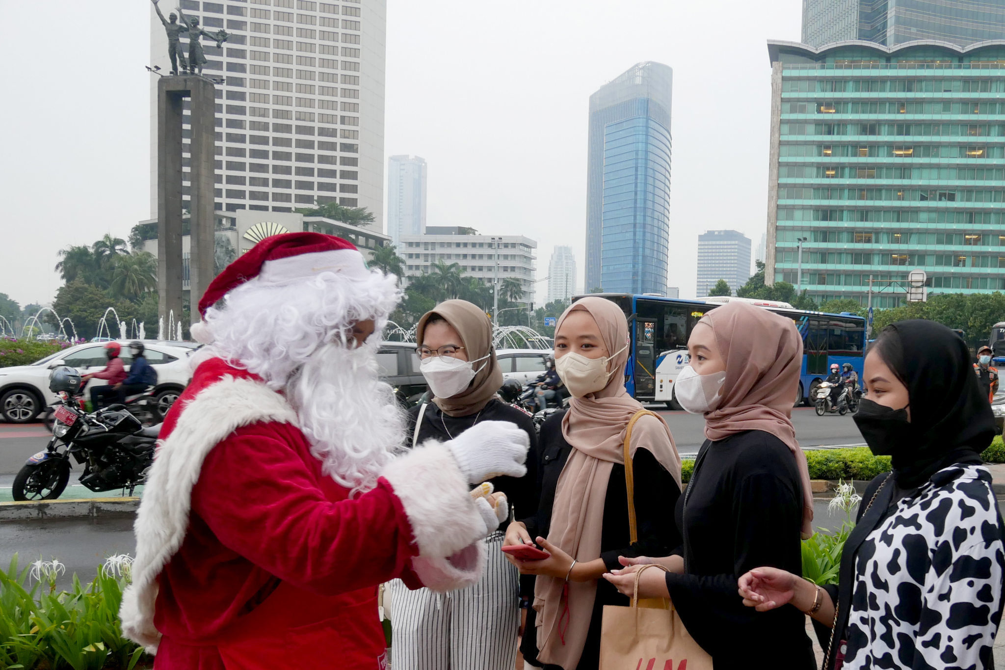 Pemeran Santa Claus membagikan permen kepada warga pada kegiatan menyambut Natal bertajuk Christmas Carol di Bundaran Hotel Indonesia, Jakarta, Selasa, 21 Desember 2021. Foto: Ismail Pohan/TrenAsia