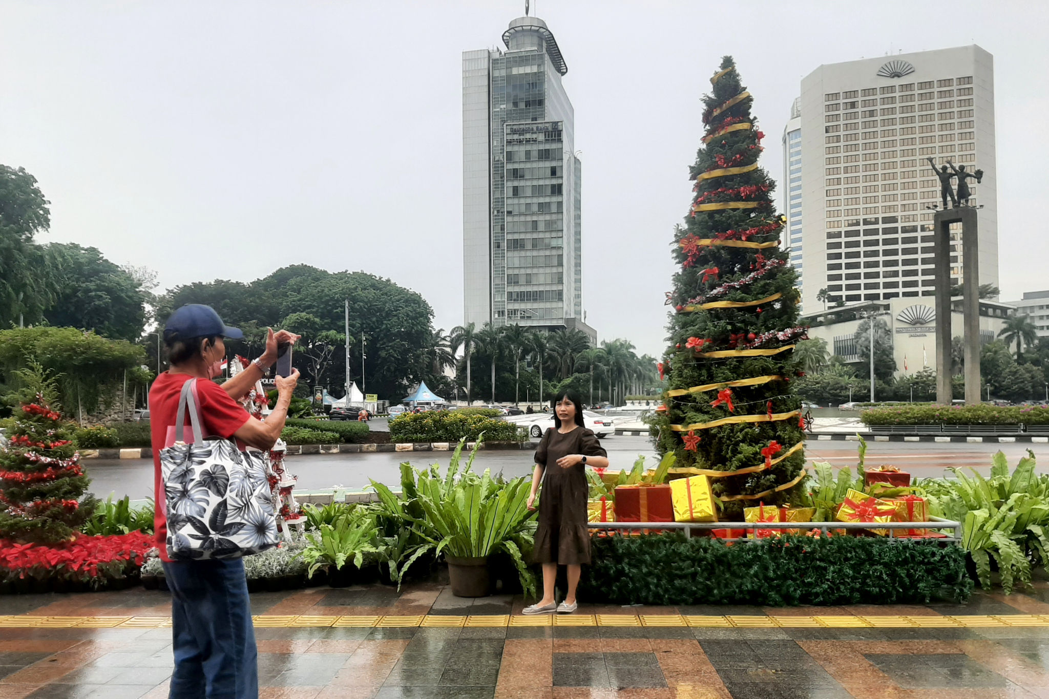 Warga berfoto dengan latar ornamen pohon Natal yang dipajang di pedestrian Bundaran HI, Jakarta, Sabtu, 25 Desember 2021. Foto: Ismail Pohan/TrenAsia