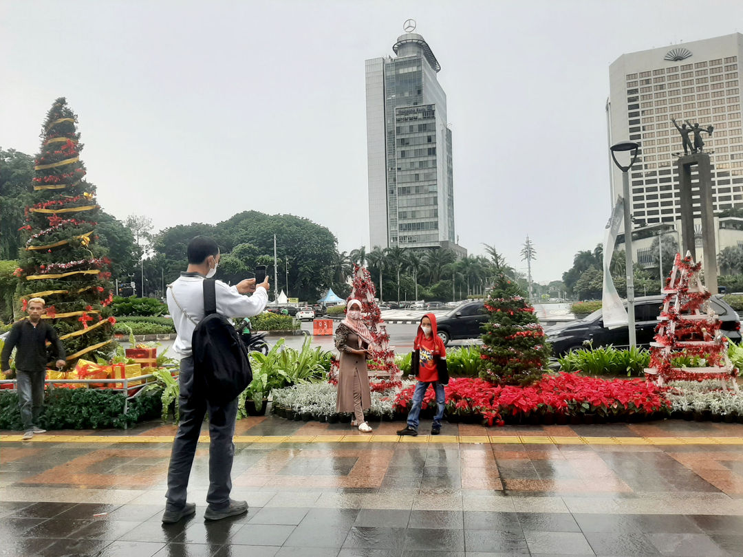 Warga berfoto dengan latar ornamen pohon Natal yang dipajang di pedestrian Bundaran HI, Jakarta, Sabtu, 25 Desember 2021. Foto: Ismail Pohan/TrenAsia