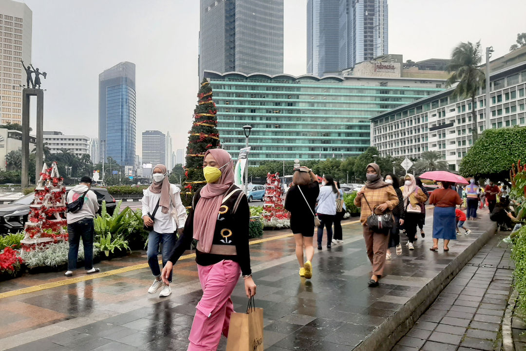 Warga melintas di dekat ornamen pohon Natal yang dipajang di pedestrian Bundaran HI, Jakarta, Sabtu, 25 Desember 2021. Foto: Ismail Pohan/TrenAsia