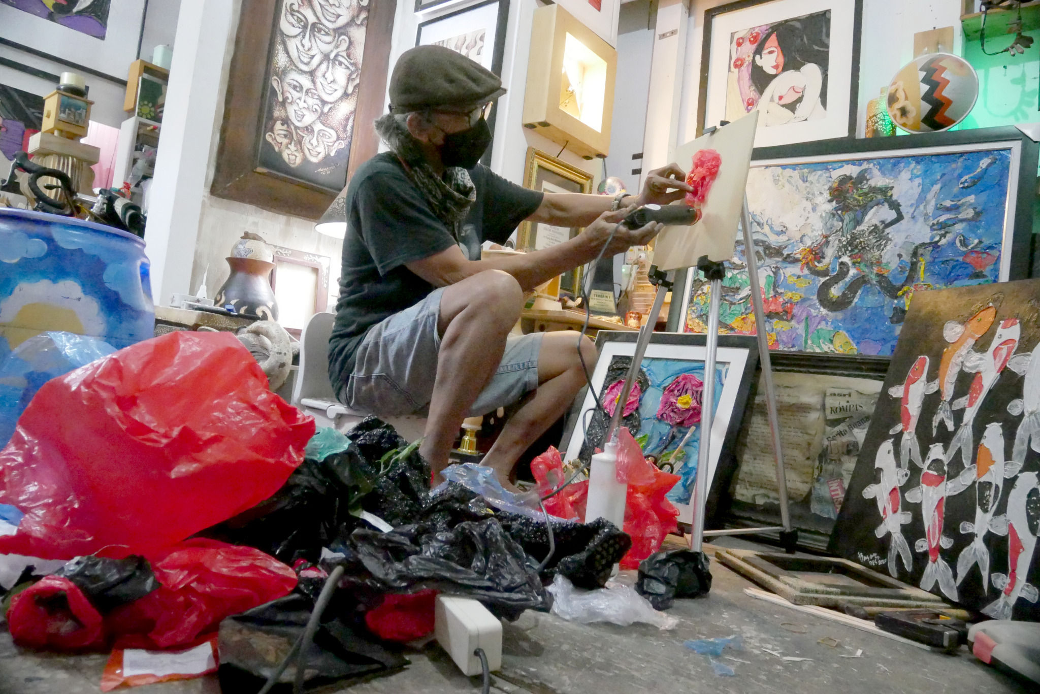 Dwiyono (66) melukis dengan memanfaatkan limbah sampah plastik di workshop galery miliknya di kawasan Rawamangun, Jakarta Timur, Kamis, 6 Januari 2022. Foto: Ismail Pohan/TrenAsia
